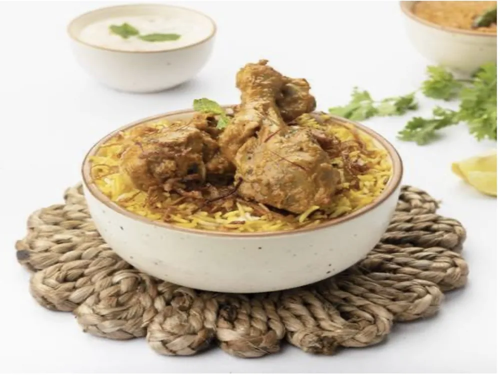 Chicken biryani in a bowl with raita