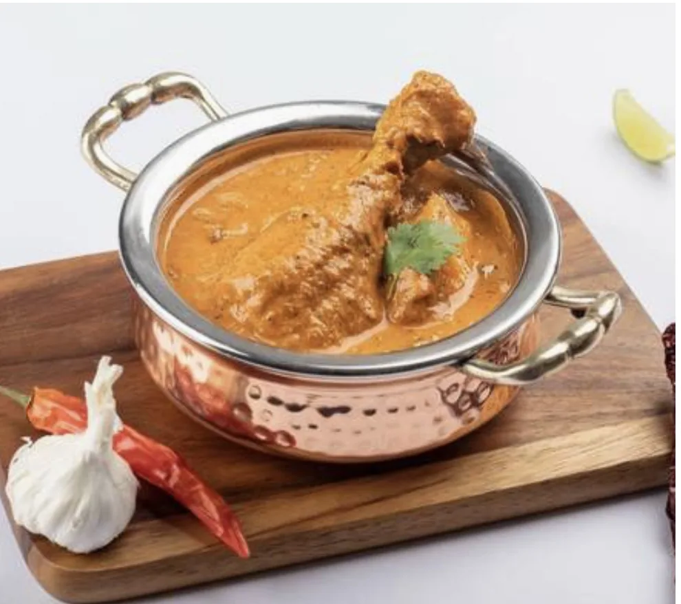 Chicken curry with a drumstick in a copper handi